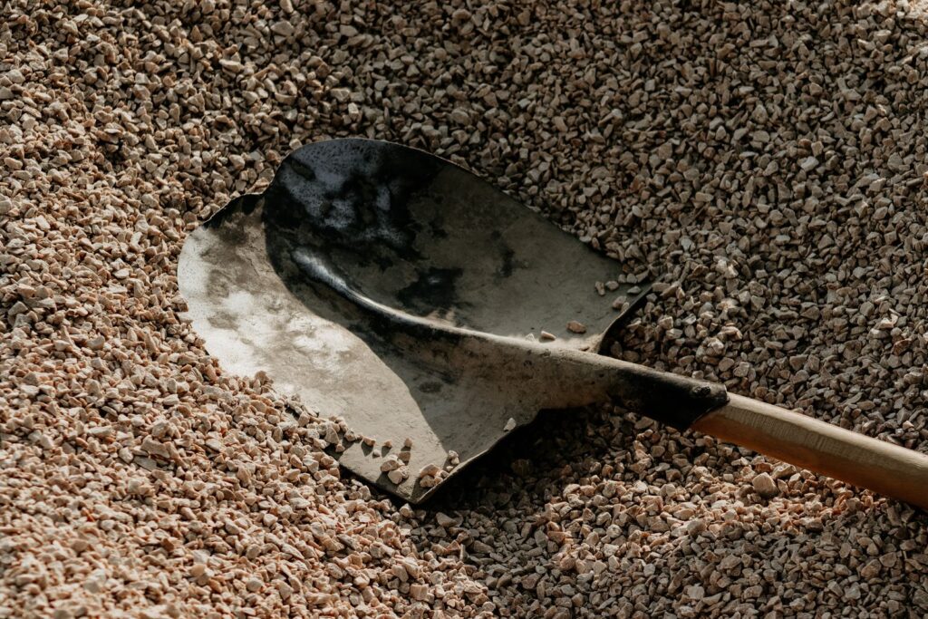 Shovel resting in a pile of landscaping gravel